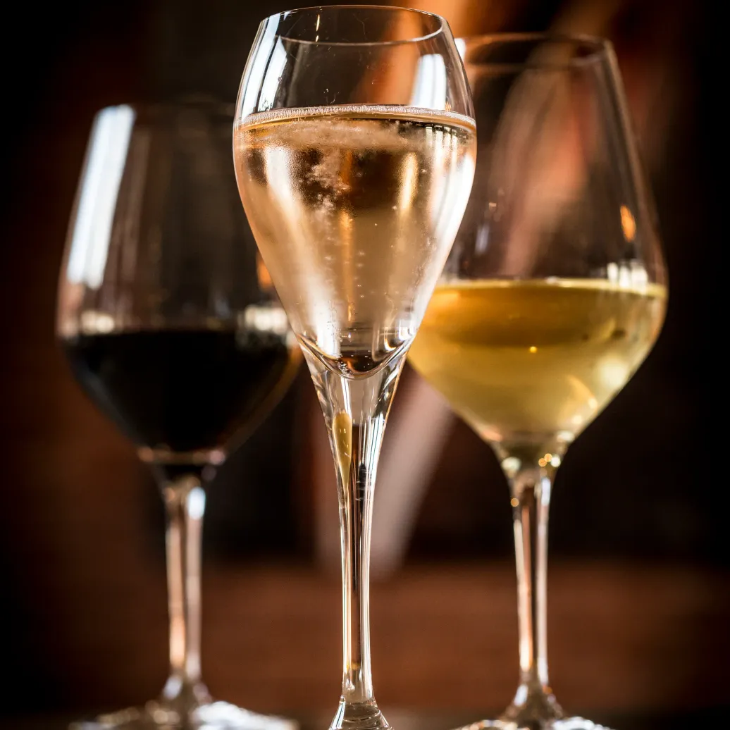 Trois verres à vin contenant des vins de couleurs différentes posés sur une surface sombre