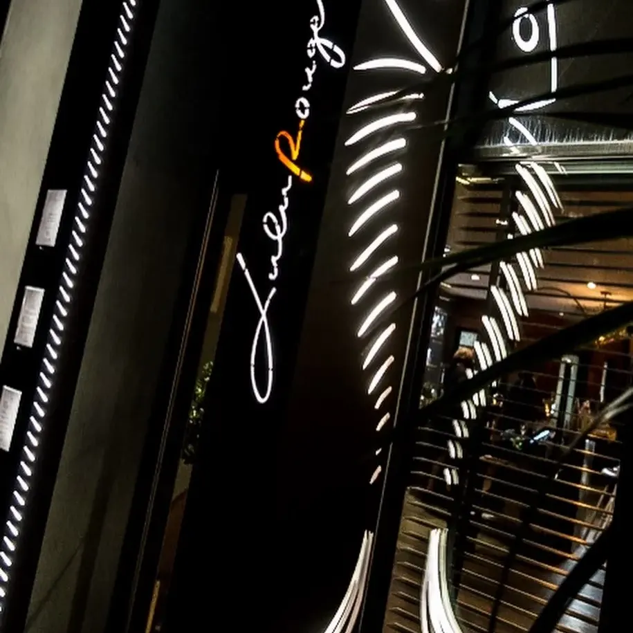 Enseigne lumineuse de restaurant avec des néons blancs et un r orange, vue depuis l'intérieur d'un établissement 
